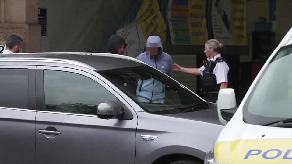 a man in a hooded sweatshirt is talking to a police officer