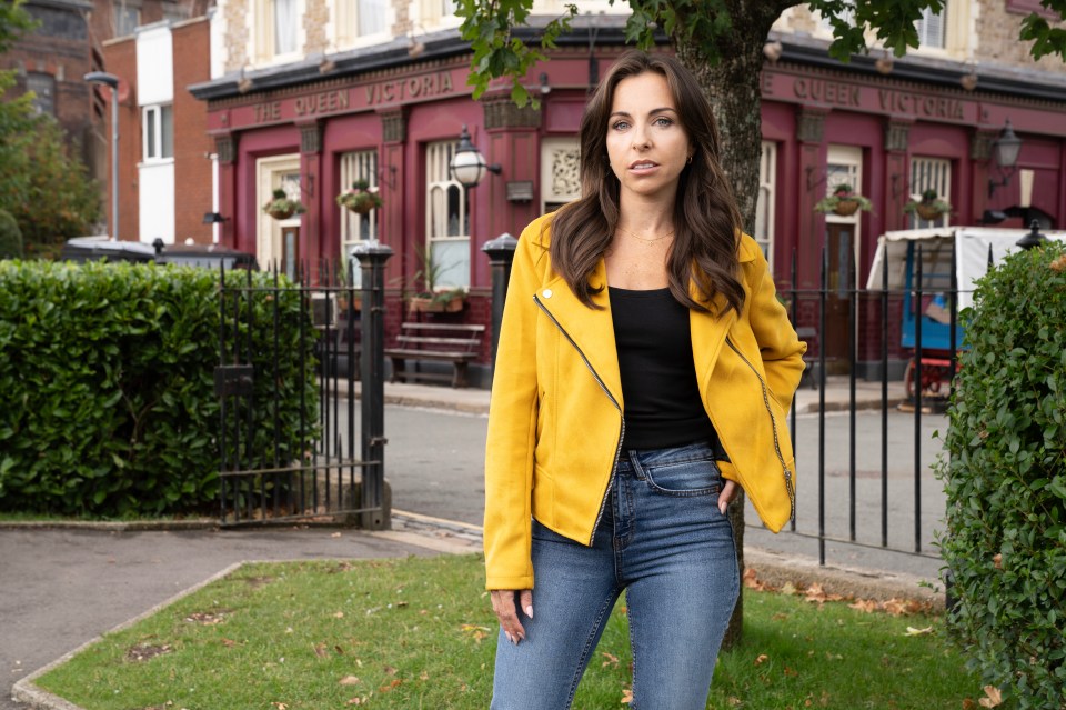 a woman in a yellow jacket stands in front of the queen victoria pub