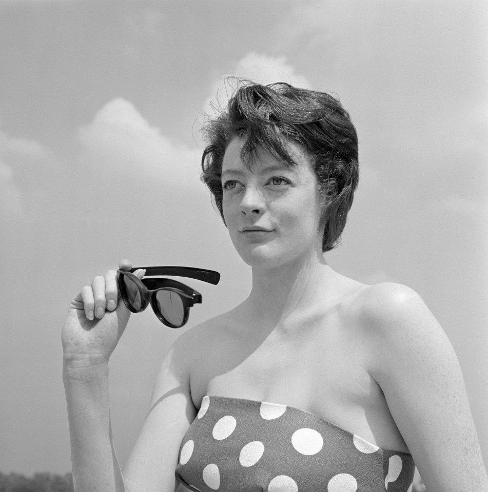 a woman in a polka dot top is holding a pair of sunglasses