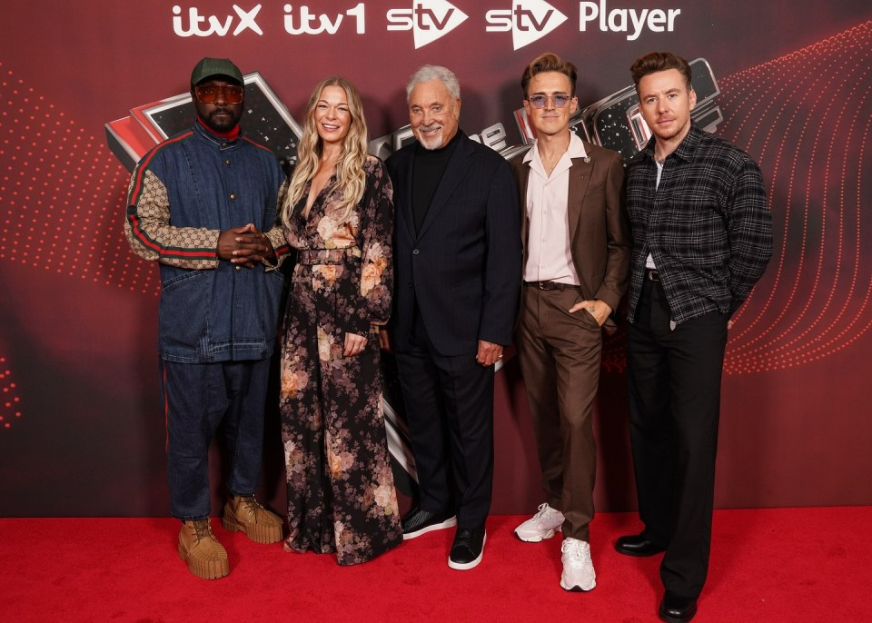 a group of people standing on a red carpet in front of a sign that says itv player