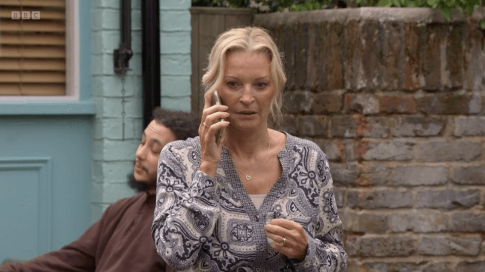 a woman talking on a cell phone in front of a bbc logo