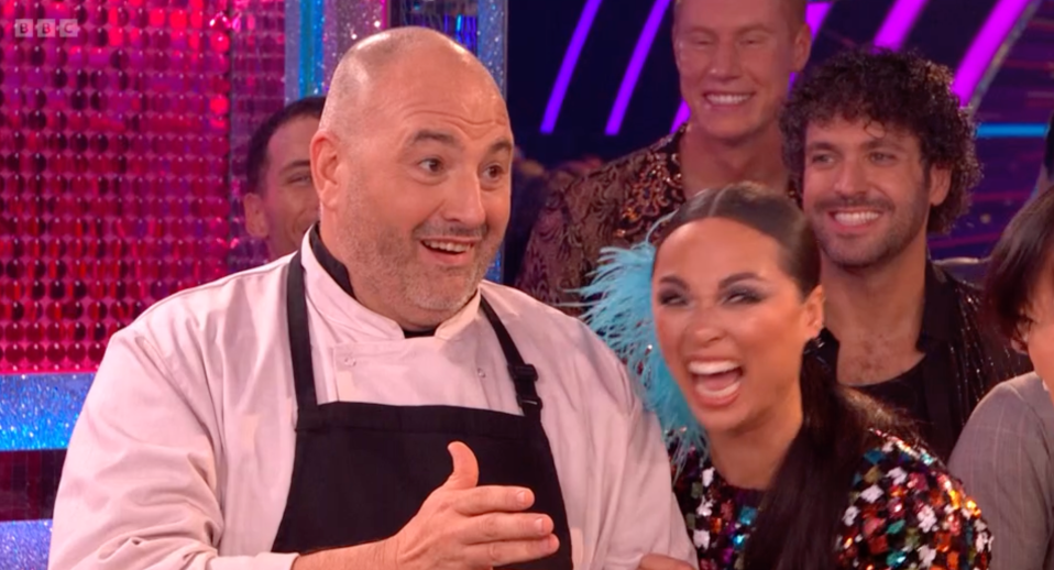 a man in an apron is laughing with a woman in a sequined dress