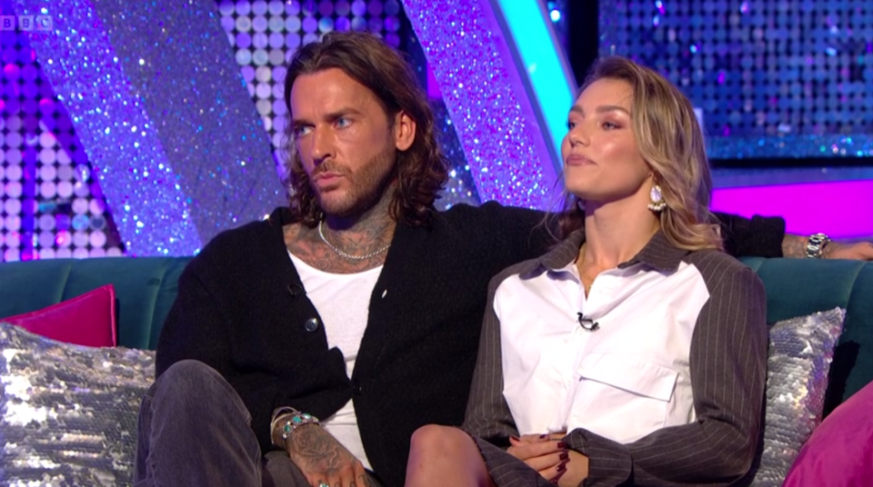 a man and a woman sit on a couch in front of a bbc logo