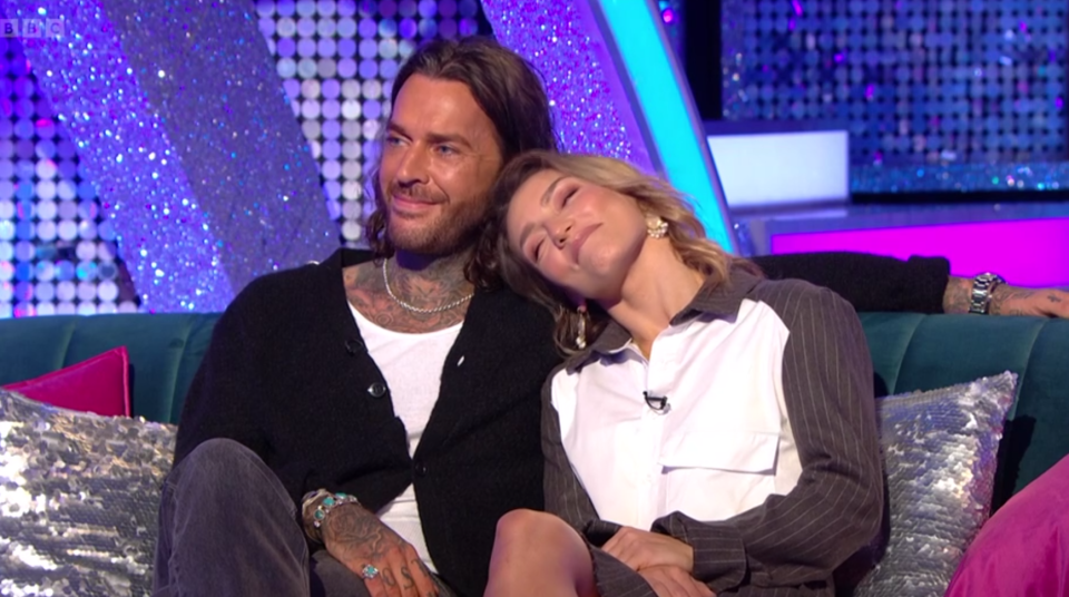 a man and a woman are sitting on a couch with a bbc logo in the background