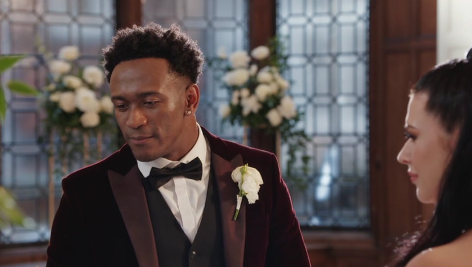 a man in a suit stands next to a woman in a wedding dress