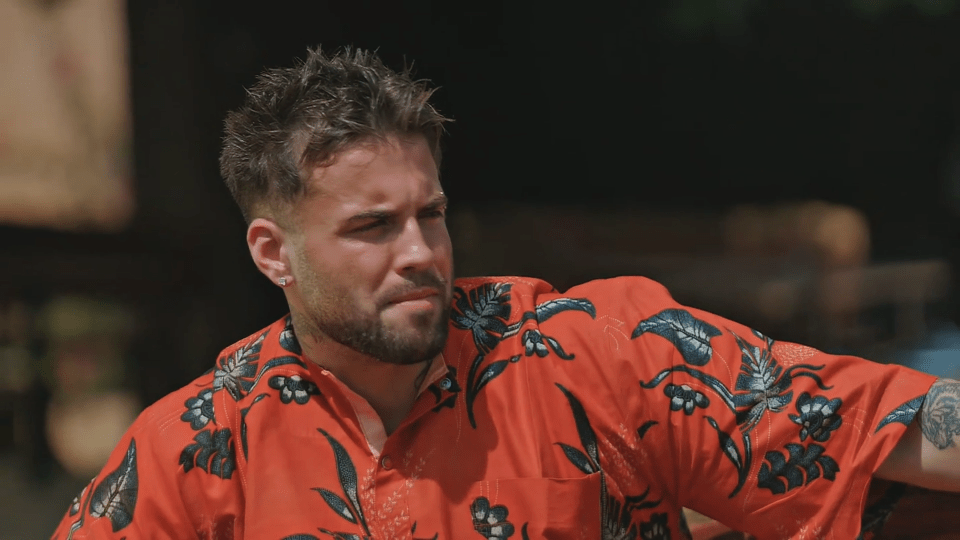 a man wearing a red shirt with flowers on it