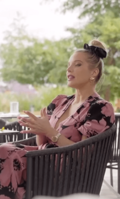 a woman in a pink floral dress is sitting in a chair