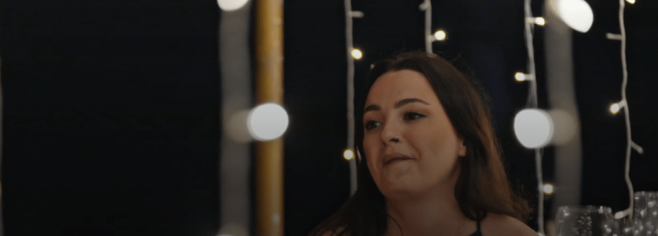 a woman sitting in front of a string of lights