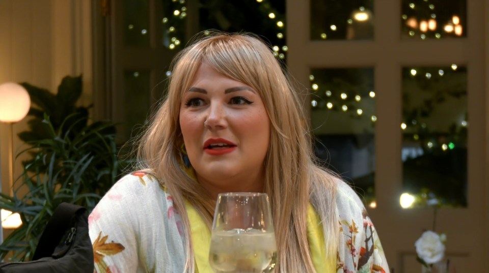 a woman sitting at a table with a glass of wine