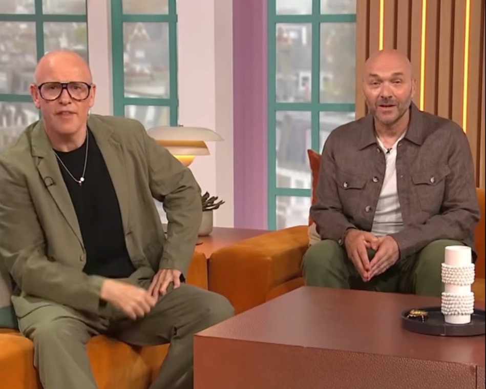 two bald men sit on a couch next to a coffee table