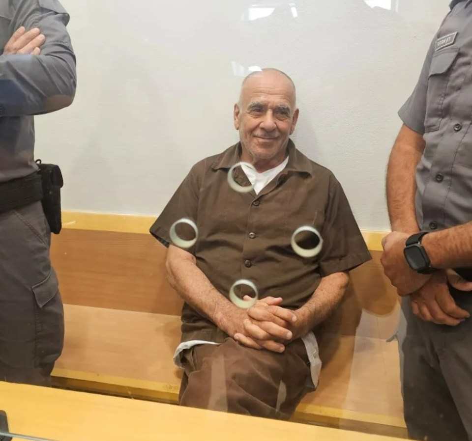 a man in a prison uniform is sitting in front of a glass wall