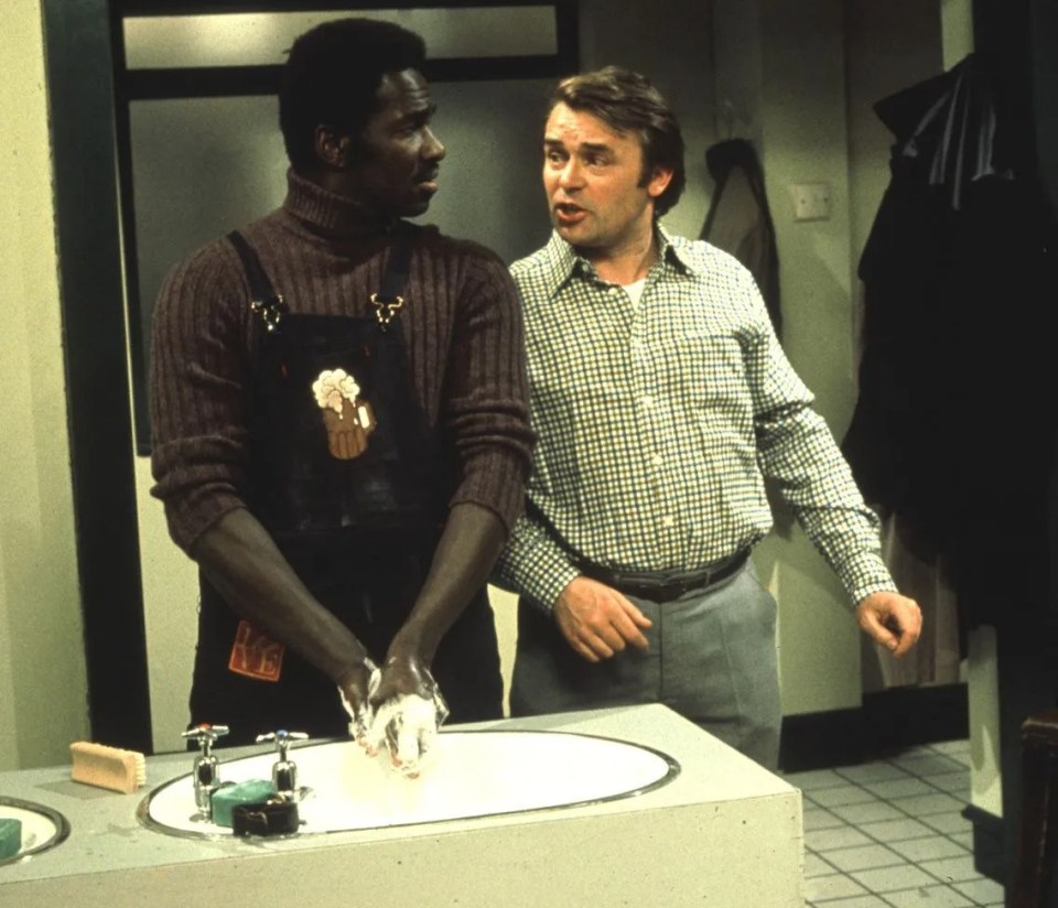 two men standing next to each other in front of a sink