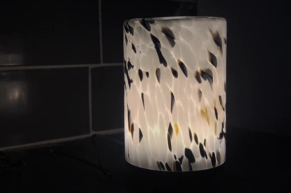 a lamp with a black and white pattern is lit up in the dark