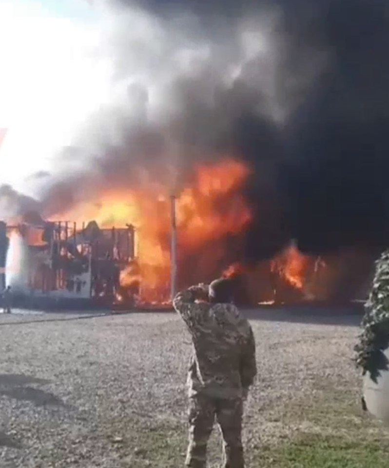 a soldier is saluting in front of a large fire .