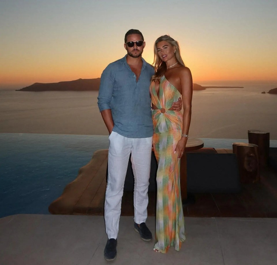 a man and a woman pose for a picture in front of the ocean