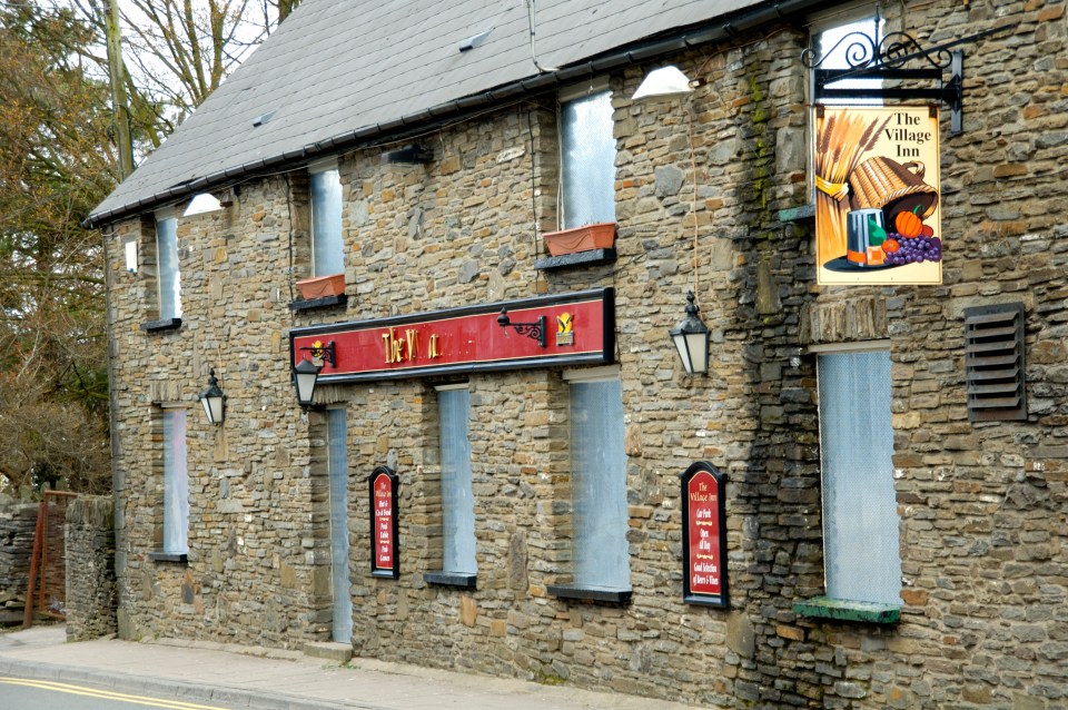 a stone building with a sign that says the village inn