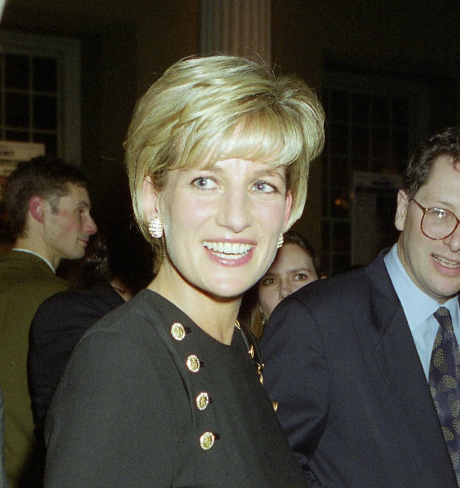 a woman in a black dress is smiling and holding a glass