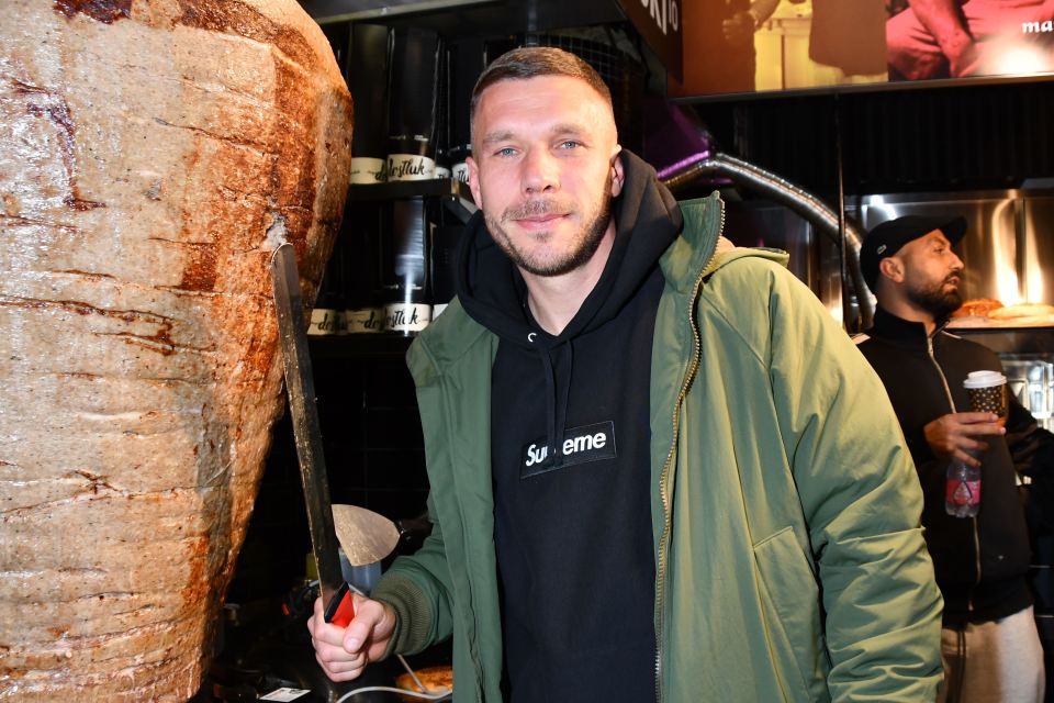 a man wearing a black supreme hoodie stands in front of a kebab machine