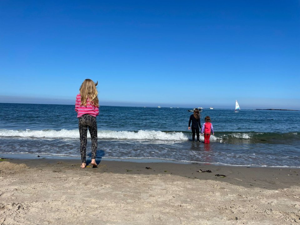 a girl with horns stands on the beach looking at the ocean