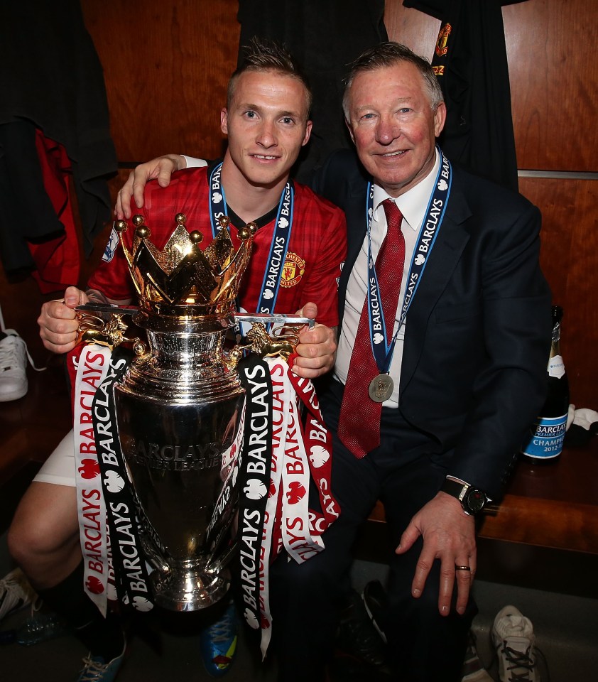 two men holding a trophy with barclays ribbons around them