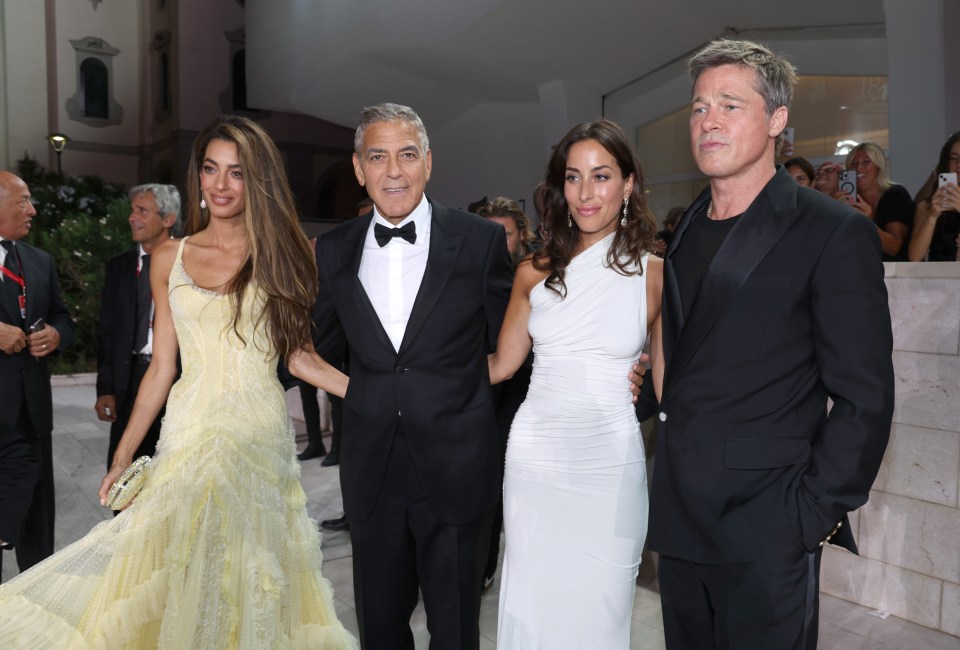 a man in a black suit stands next to two women in white dresses