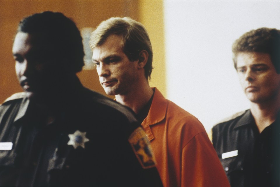 a man in an orange shirt with a sheriff 's badge on his shoulder