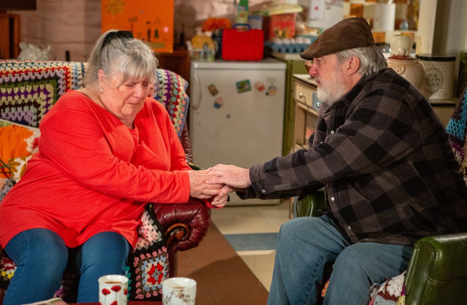 a man and a woman sit on a couch holding hands