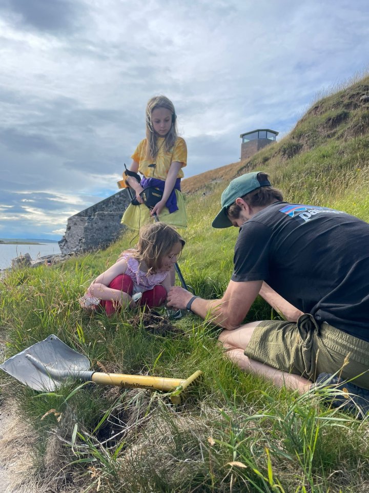 a man wearing a patagonia shirt sits in the grass with two children