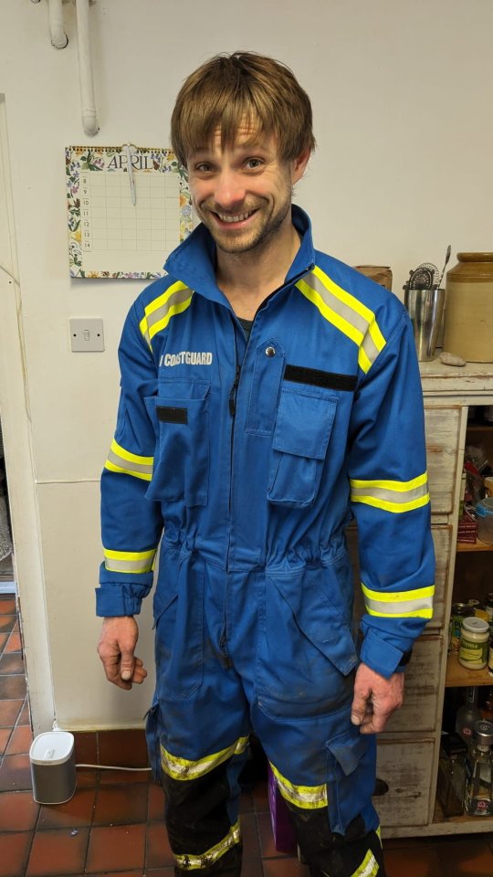 a man wearing a blue and yellow jumpsuit that says coastguard