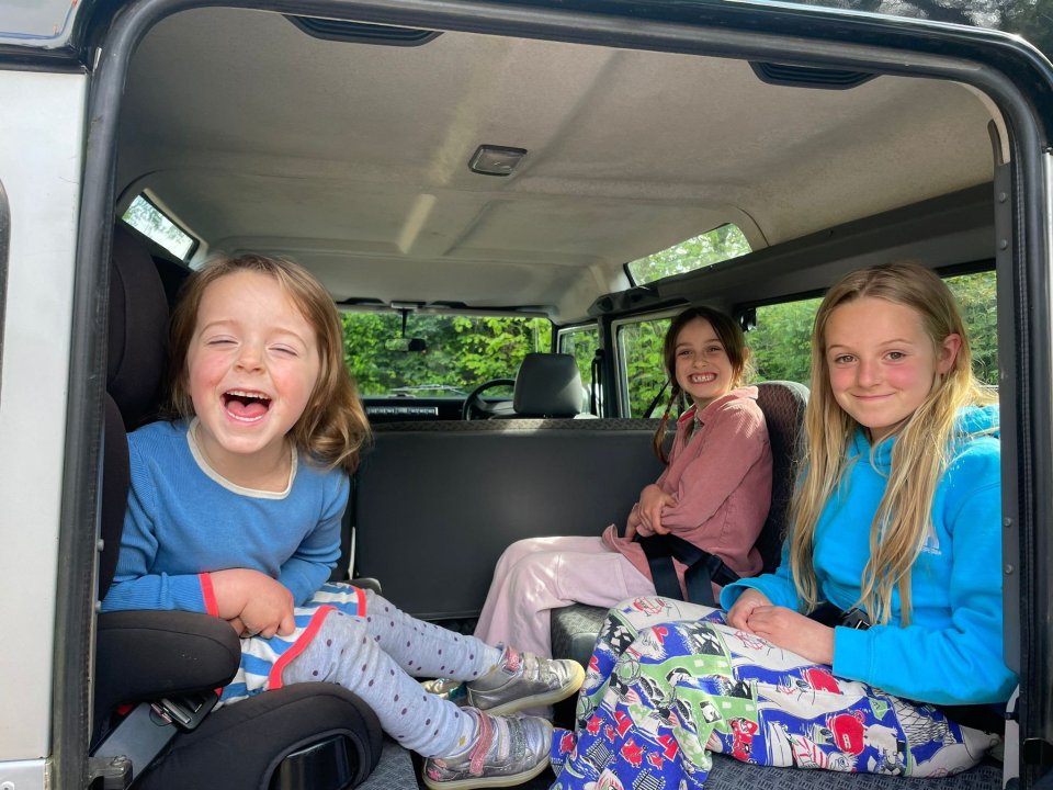 three young girls are sitting in the back seat of a land rover