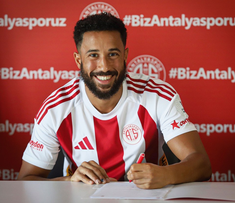 a man in a red and white adidas shirt signs a document