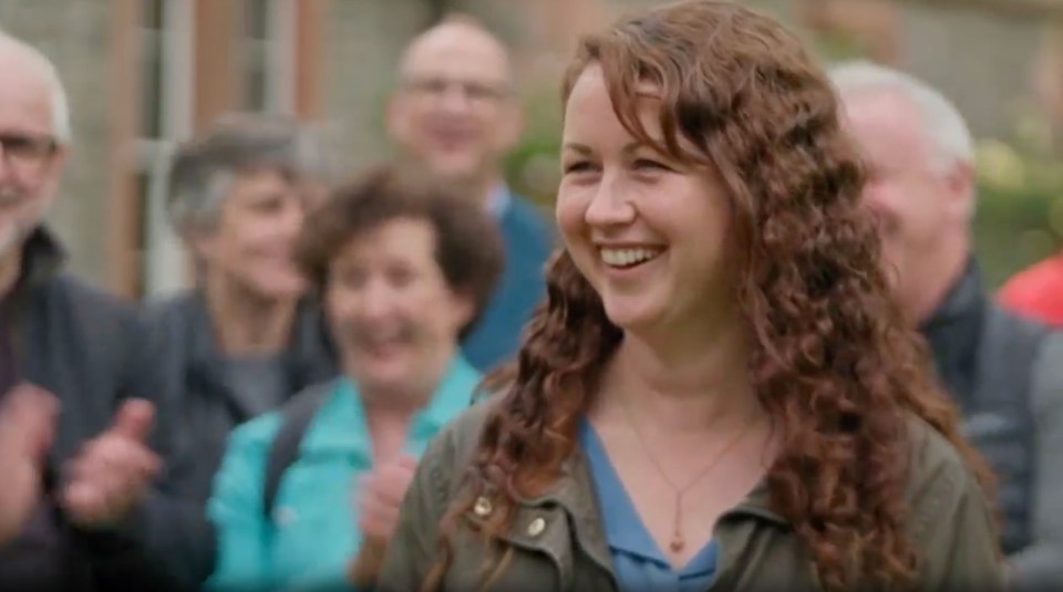 a woman is smiling in front of a crowd of people .