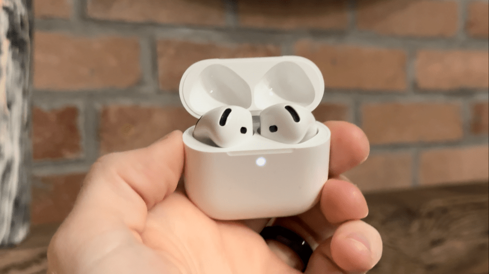 a person is holding a pair of airpods in their hand