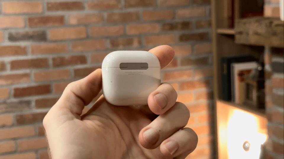 a person is holding a white case with a brick wall in the background