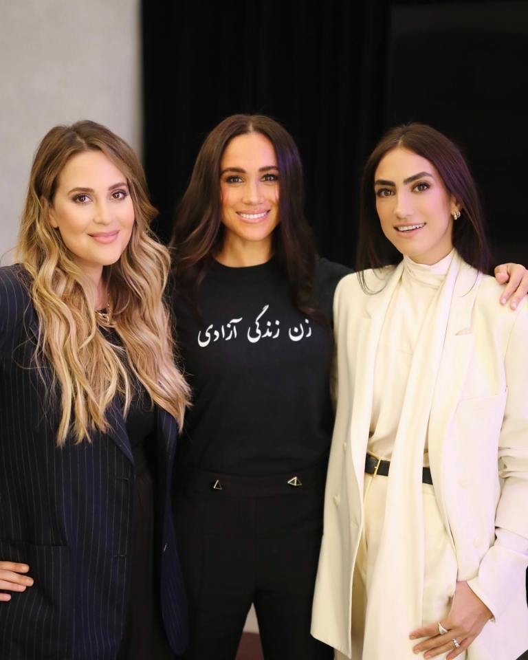 three women are posing for a picture and one of them is wearing a shirt with arabic writing on it