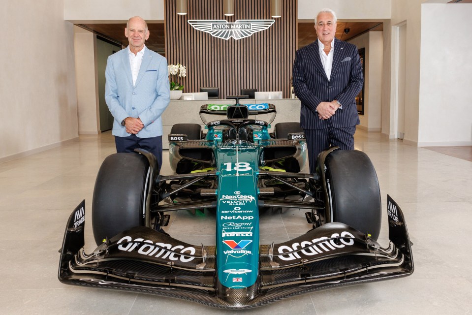 two men standing next to a green race car with the number 18 on it