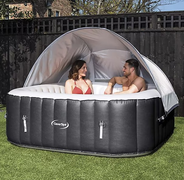 a man and woman are sitting in a coverspa hot tub