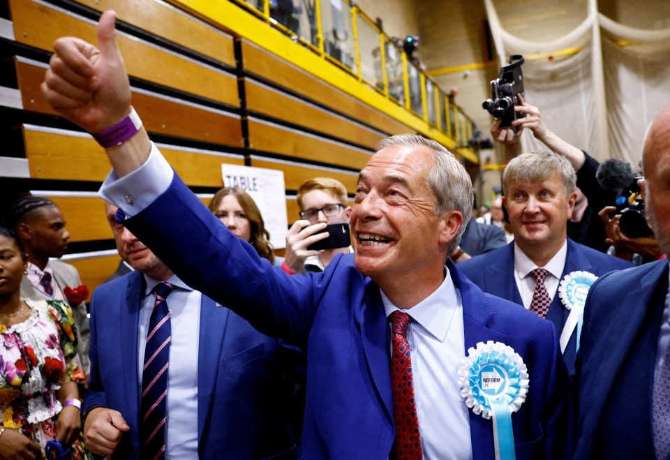 a man in a blue suit is giving a thumbs up