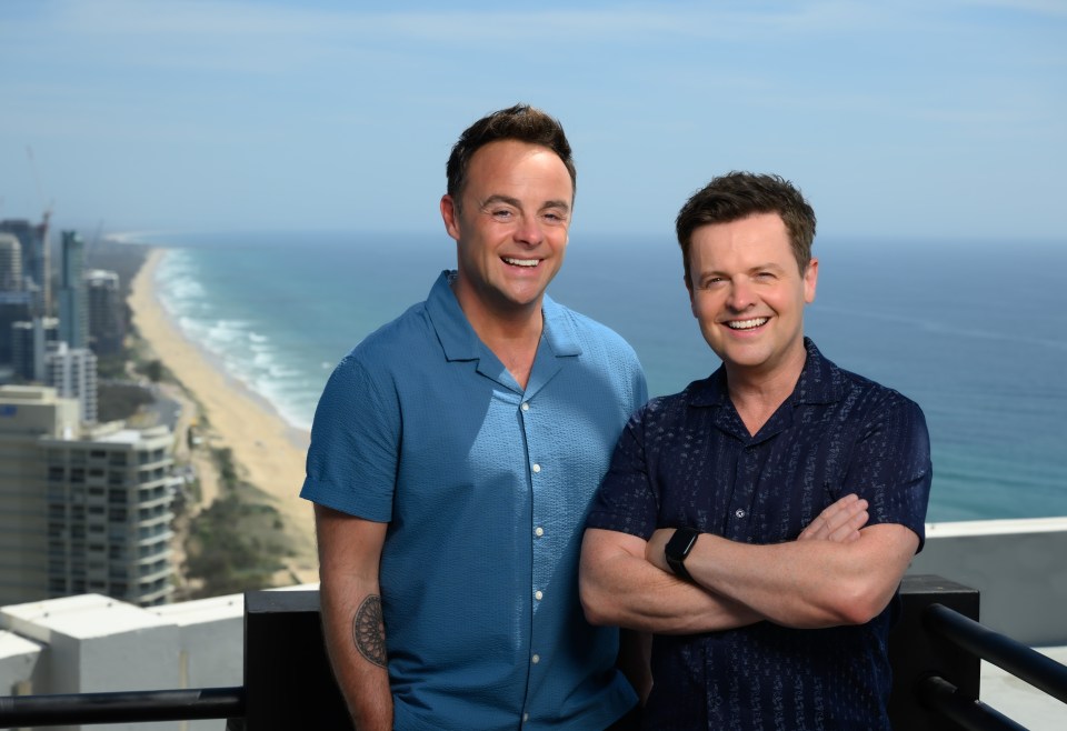 two men standing next to each other with the ocean in the background