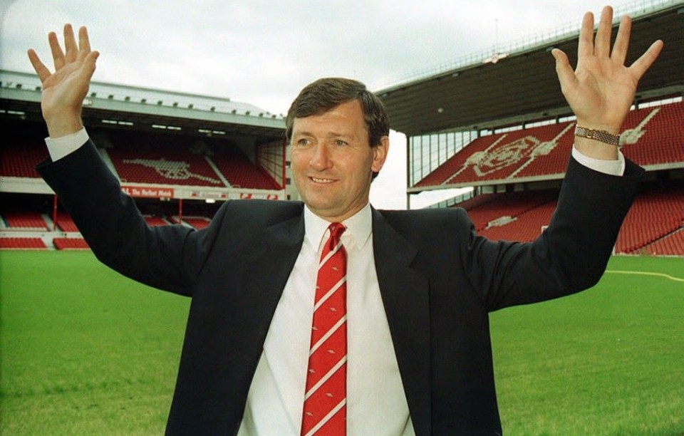 a man in a suit and tie stands in front of a stadium