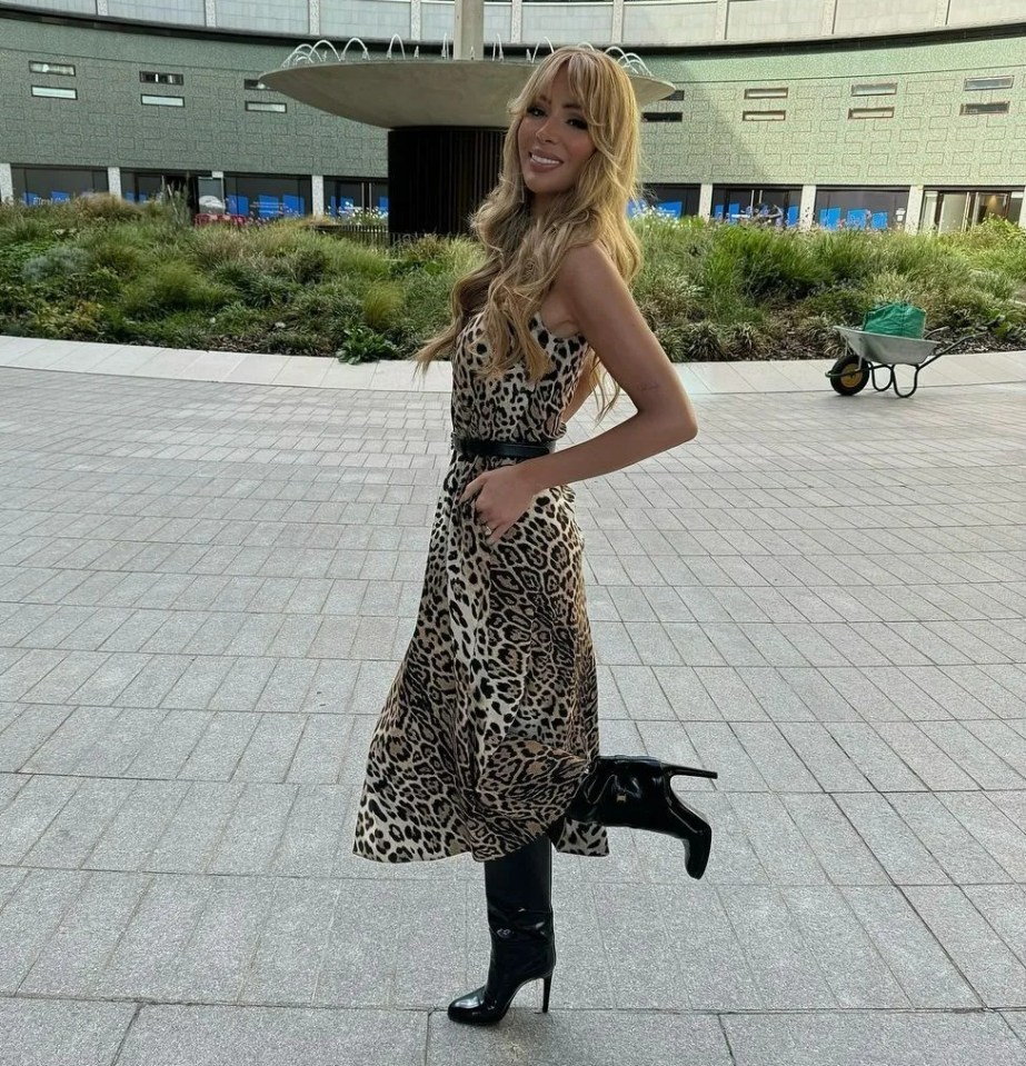 a woman in a leopard print dress stands in front of a large building