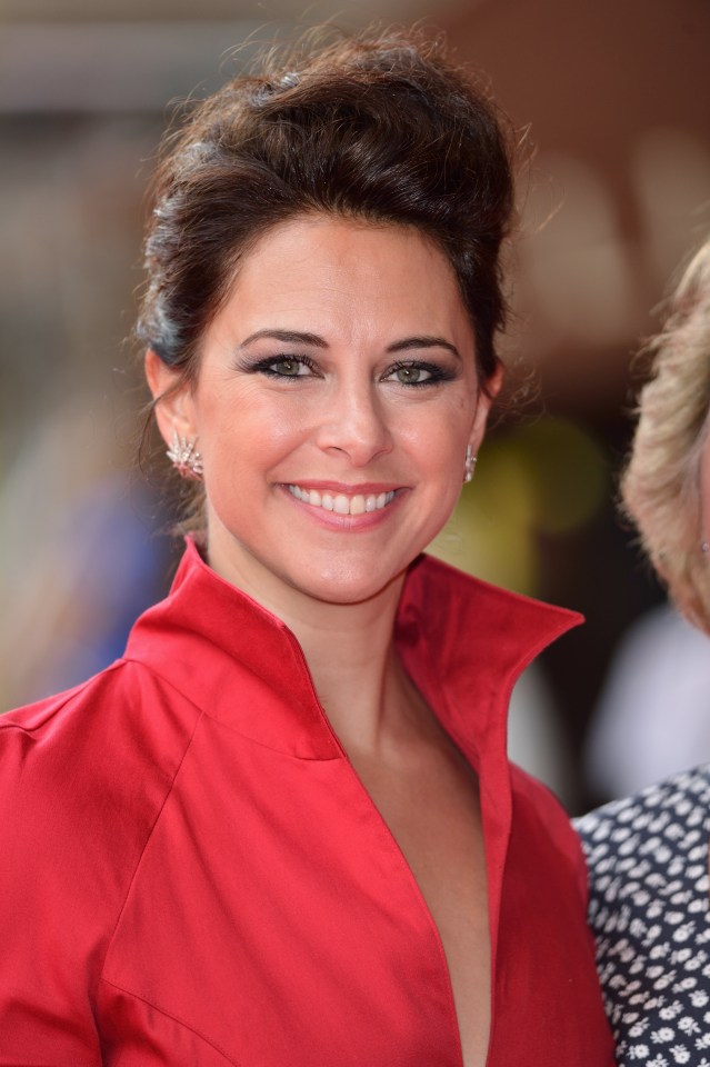 a woman wearing a red shirt and earrings smiles for the camera