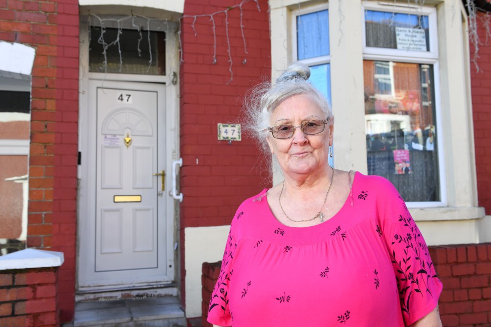 a woman stands in front of a house with the number 47 on the door