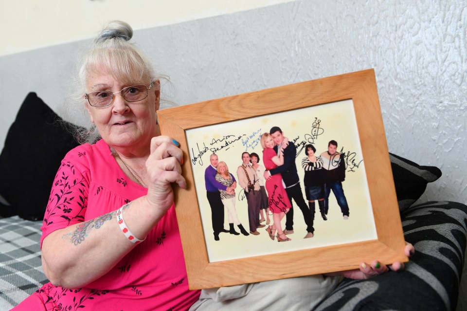 a woman is holding a framed picture of a group of people