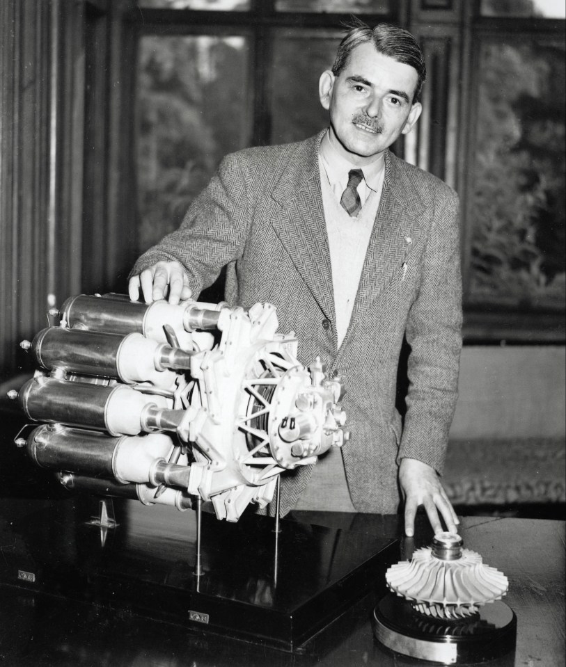 a man in a suit stands next to a model of an engine that says cb on it