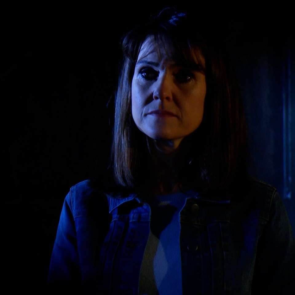 a woman in a blue jacket is standing in the dark