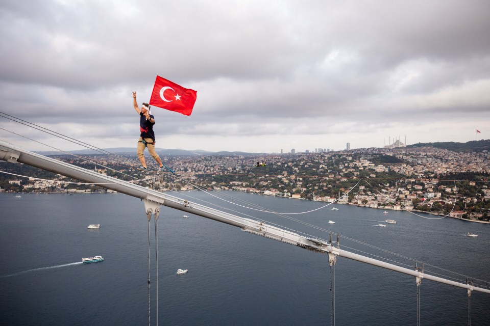 a man wearing a red bull shirt is walking on a tightrope