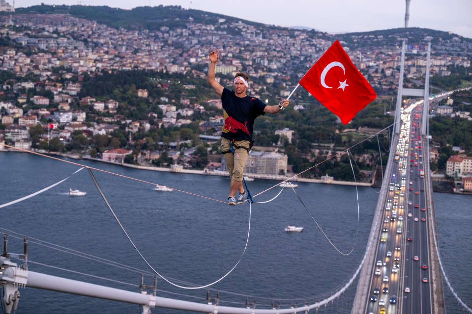 a man on a tightrope holding a flag with the letter c on it