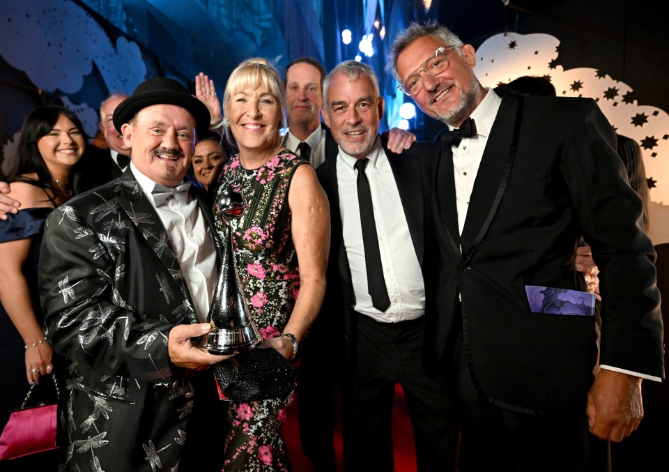 a group of people posing for a picture with one man holding a trophy