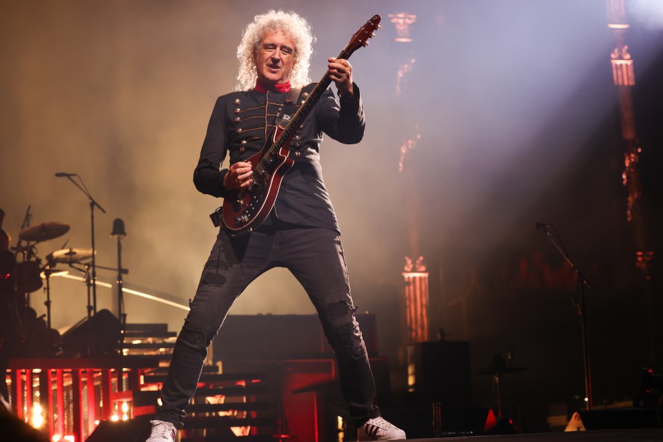 a man with white hair is playing a guitar on a stage